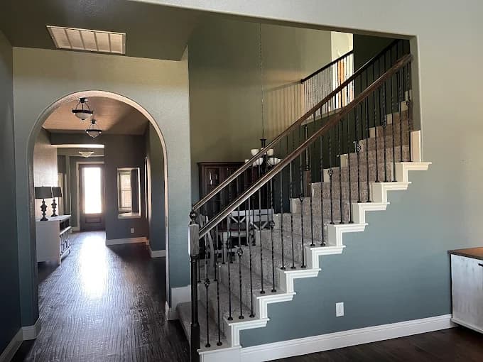 This is an image from MJ Workforce Solutions LLC, located in Texas. The interior hallway and staircase showcase blue-green painted walls, white trim, and a carpeted stairway with iron balusters.
