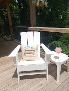 Deck staining by CertaPro Painters of Hickory in Hickory, NC. The image shows a brown wood deck with a white chair and side table beneath trees.