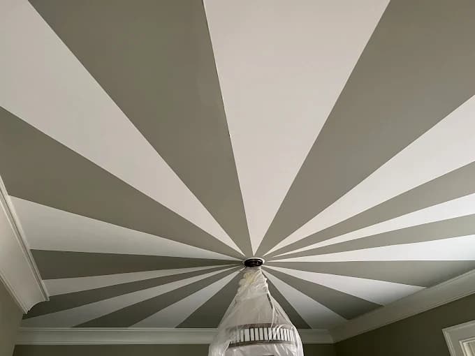 Interior painting project by Recinos Painting in Apex, NC. The image shows a gray-and-white sunburst ceiling with crown molding and a covered chandelier.
