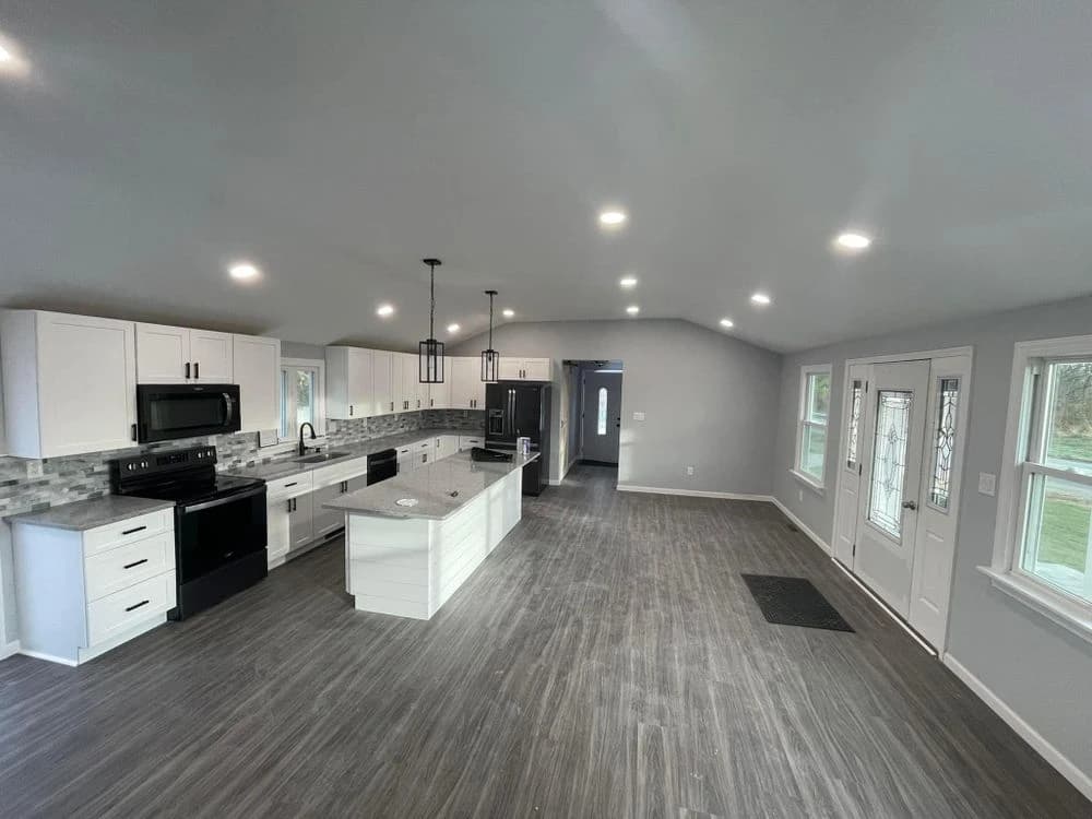 Spacious modern kitchen with recessed lighting, gray flooring, and white cabinetry, demonstrating interior renovation and painting services by Painting Plus Home Improvement LLC.