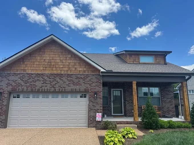 Painting project by New Direction Painting in Franklin, Tennessee. The image shows a brick home with dark-painted entry trim.