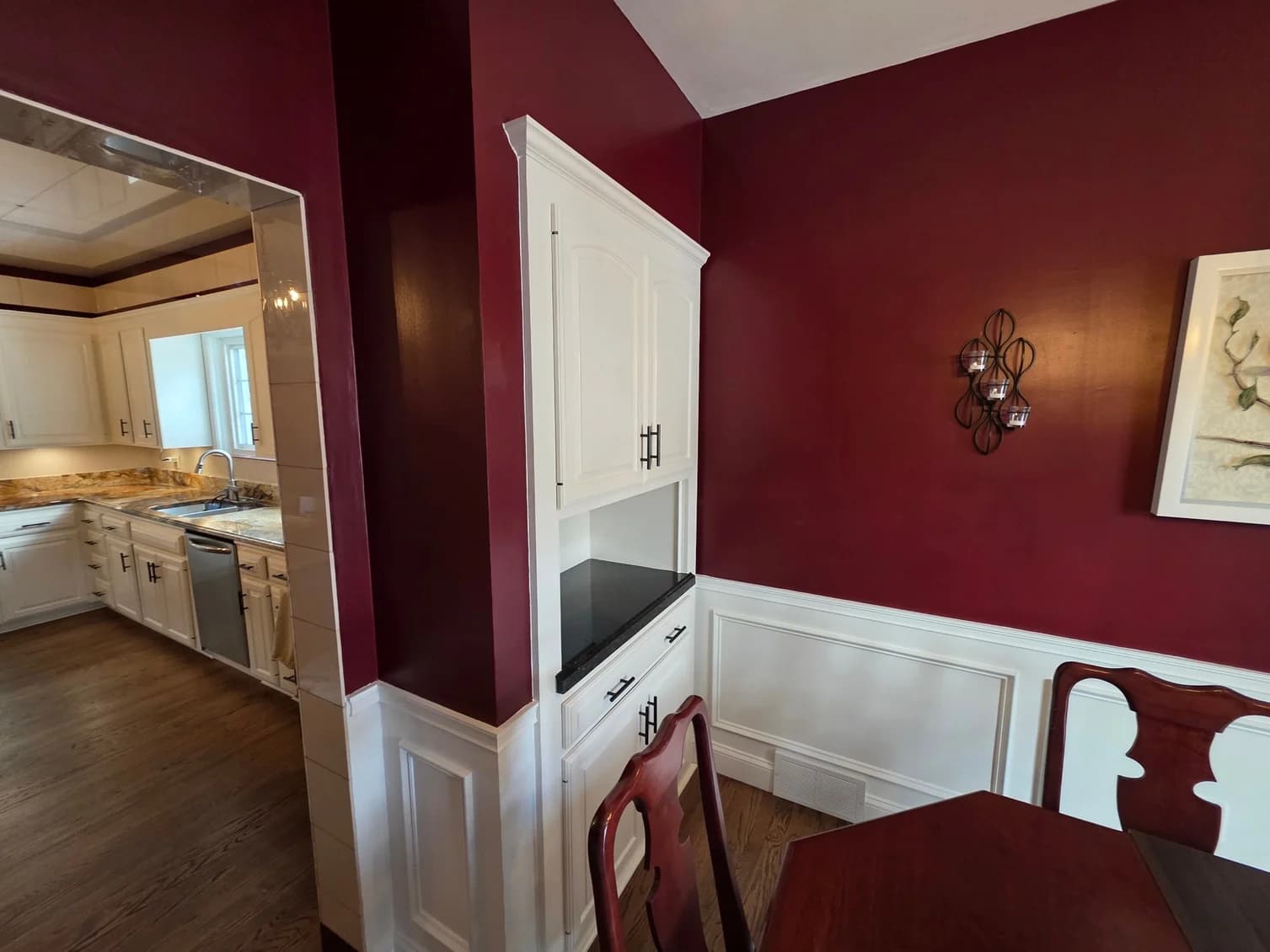 This is an image from Resurrection Painting LLC, located in Ohio. The image shows a freshly painted dining room with deep red accent walls, white wainscoting, built-in cabinetry, crown molding, and clean interior wall finishes.