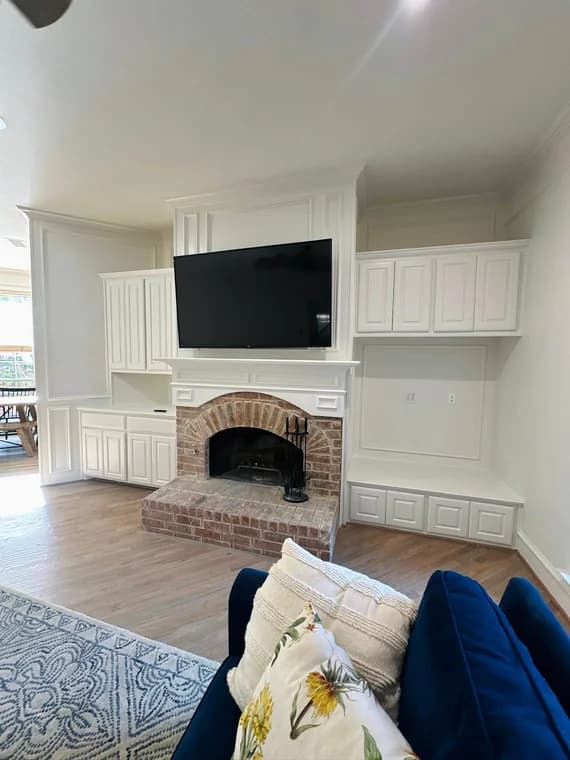 This is an image from Spray Tex Painting, located in Texas. The picture shows a living room with a brick fireplace, built-in white cabinetry, and a mounted TV above the mantel.