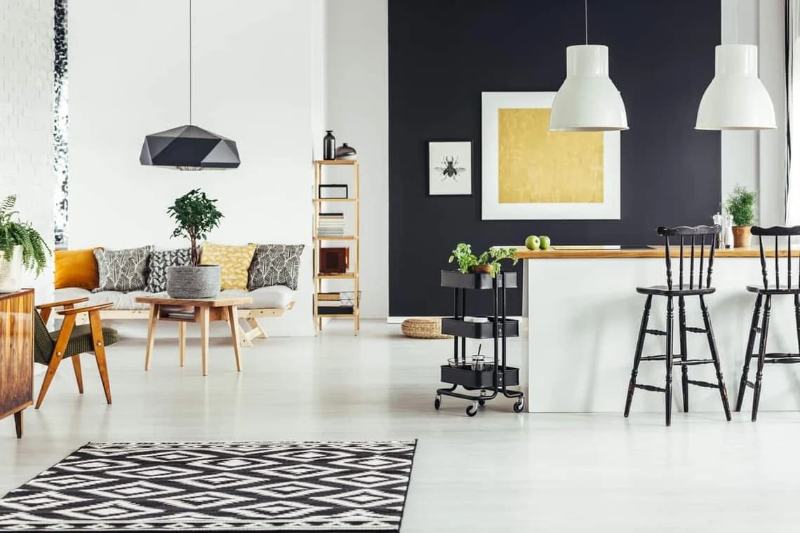 "This is an image from Roll City Painting, located in Texas. The interior space displays a bold black accent wall, white cabinetry, modern décor, and natural wood furniture."