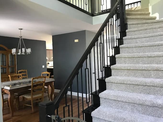 Interior painting project by Roca's Painters LLC in Mebane, North Carolina. The image shows a dining room beside carpeted stairs with a dark railing.