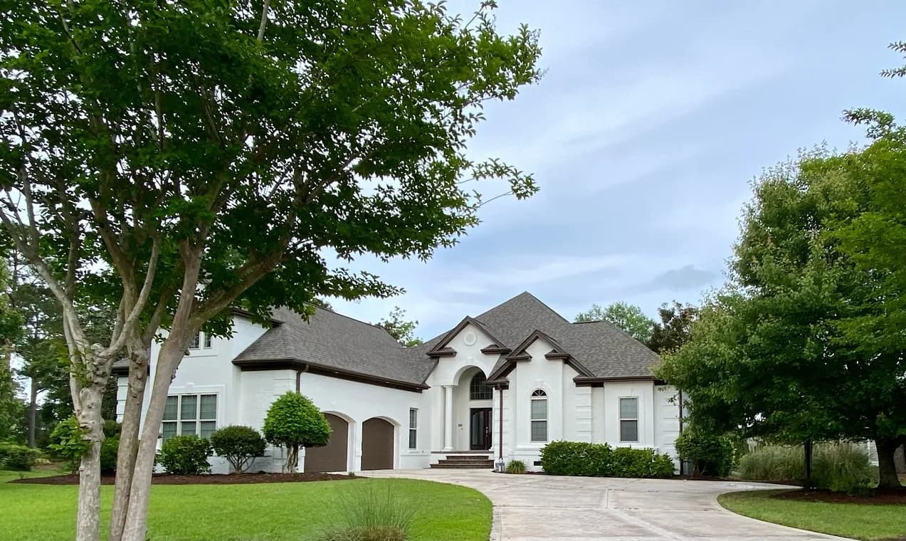 Exterior painting project by CertaPro Painters of Wilmington NC in Wilmington, North Carolina. The image shows a white stucco home with arched windows and trees.