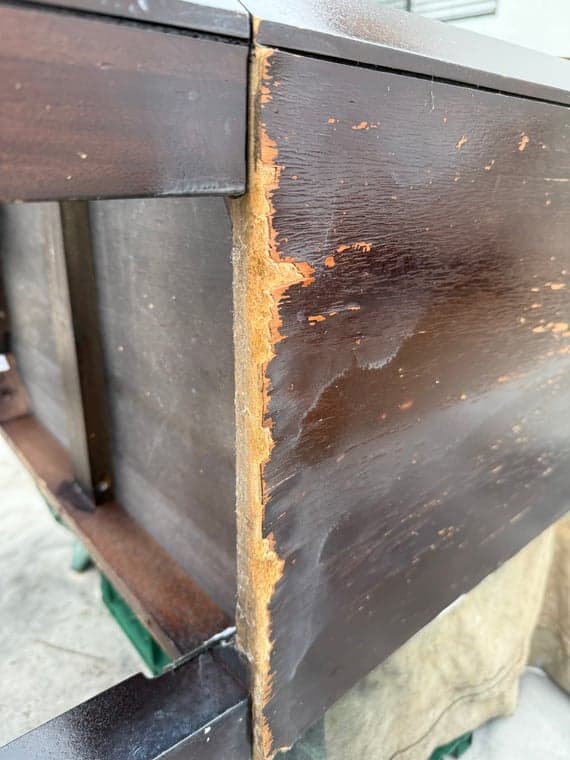 Close-up view detailing the deterioration on the dark wood vanity base edge
