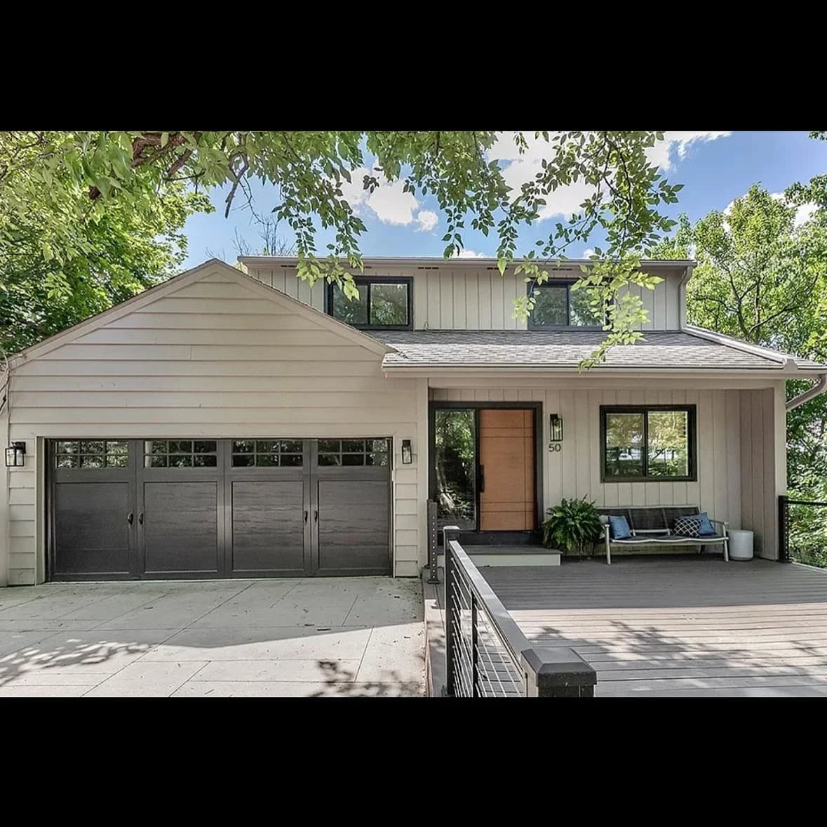 This is an image from 216 Painting, located in Ohio. The image shows a newly painted covered deck with gray flooring, white railings, and a stone fireplace feature wall with a mounted outdoor television.