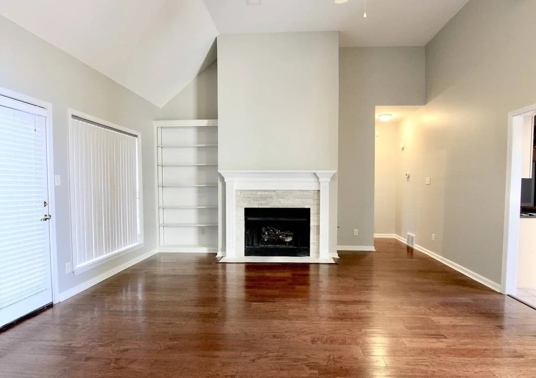 Interior painting by B Quality Painting LLC in Arlington, Tennessee. The image shows light gray walls, white trim, a fireplace, and dark wood floors.
