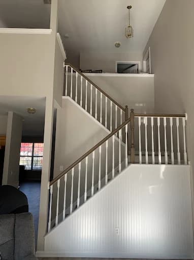 This is an image from T Whitaker Painting in New Jersey. It displays a cleanly painted staircase area with white spindles and neutral gray walls.