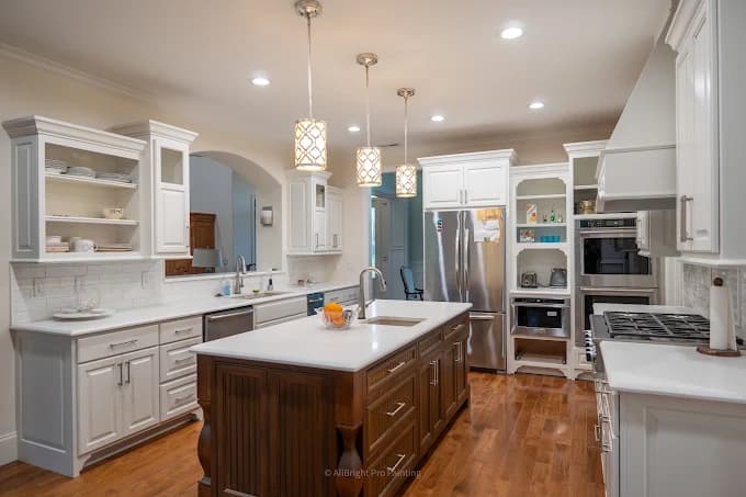 Cabinet painting by AllBright Pro Painting in Smyrna, Tennessee. The image shows a white kitchen with a dark wood island and hardwood floor.