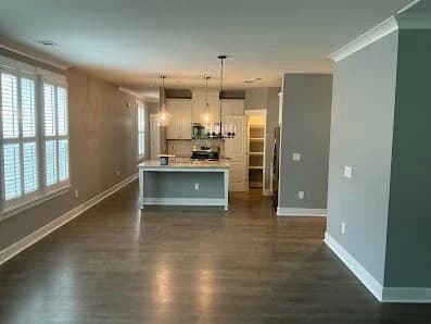 Interior painting project by CertaPro Painters of Durham, NC in Durham, NC. The image shows gray walls, white trim, dark floors, and an open kitchen.
