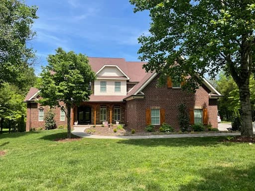 Painting project by Good Faith Painting Company in Knoxville, Tennessee. The image shows a red brick home with cream trim and a green lawn.