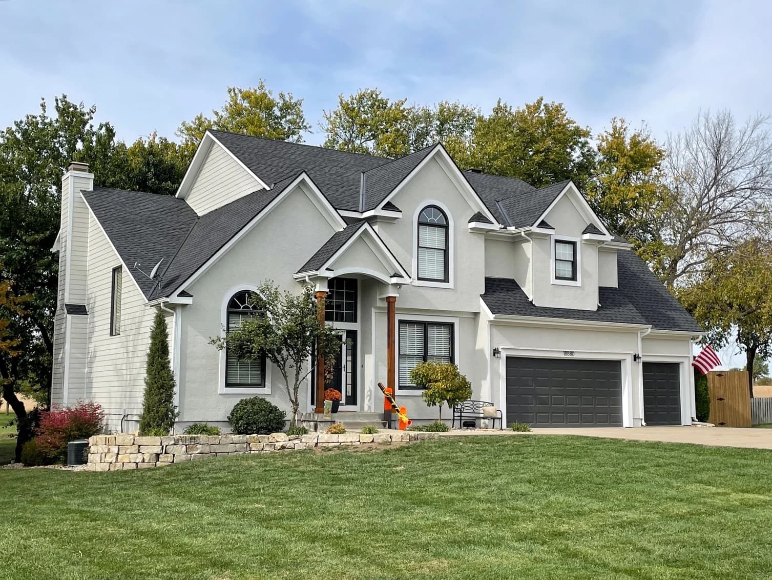 This is an image from Brogan Painting & Remodeling. The image shows a light gray stucco home with crisp white trim and dark gray garage doors after a full exterior repaint.
