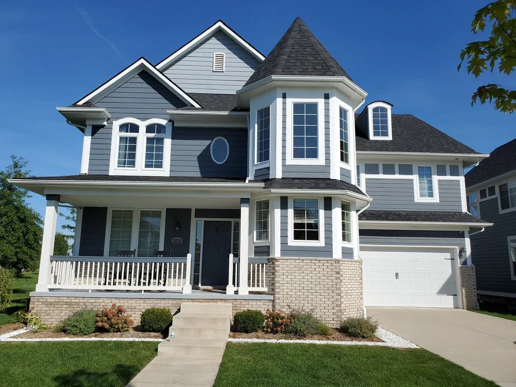 This is an image from AM Painting LLCcompany, located in Roseville, MI The image is a  freshly painted two-story home with gray siding, white trim, and dark shingle roof by AM Painting in Michigan.