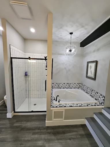 This is an image from Skywalkers Painting & Repairs, located in Ohio. The image shows a modern bathroom remodel with white subway tile shower walls, a built-in soaking tub with mosaic tile surround, and updated light gray painted walls.