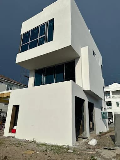 This is an image from Falcon Remodeling Express LLC company, located in Fort Walton Beach, FL. The image is a newly painted stucco exterior of a modern coastal home with raised foundation, double French doors, and clean white finish near sandy terrain