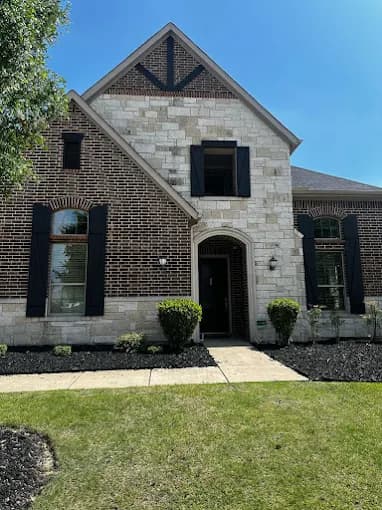 This is an image from MJ Workforce Solutions LLC, located in Texas. The exterior photo displays a brick and stone home with black shutters and well-kept front landscaping.