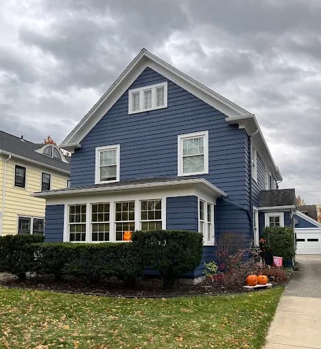 This is an image from CertaPro Painters of WNY, located in New York. The exterior image shows a two-story home painted in deep blue with white trim.