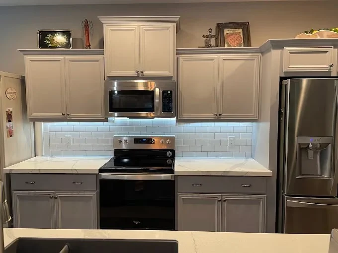 Painting work by McLain's Painting in Knoxville, Tennessee. The image shows a gray kitchen with white tile and dark appliances.