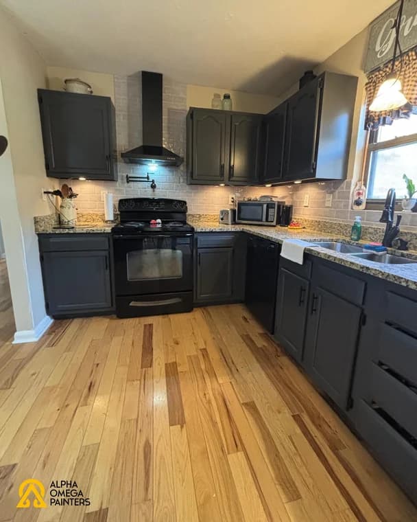 Interior painting project by Alpha Omega Painters LLC in Burnsville, North Carolina. The image shows dark kitchen cabinets, counters, wood floors, and windows.