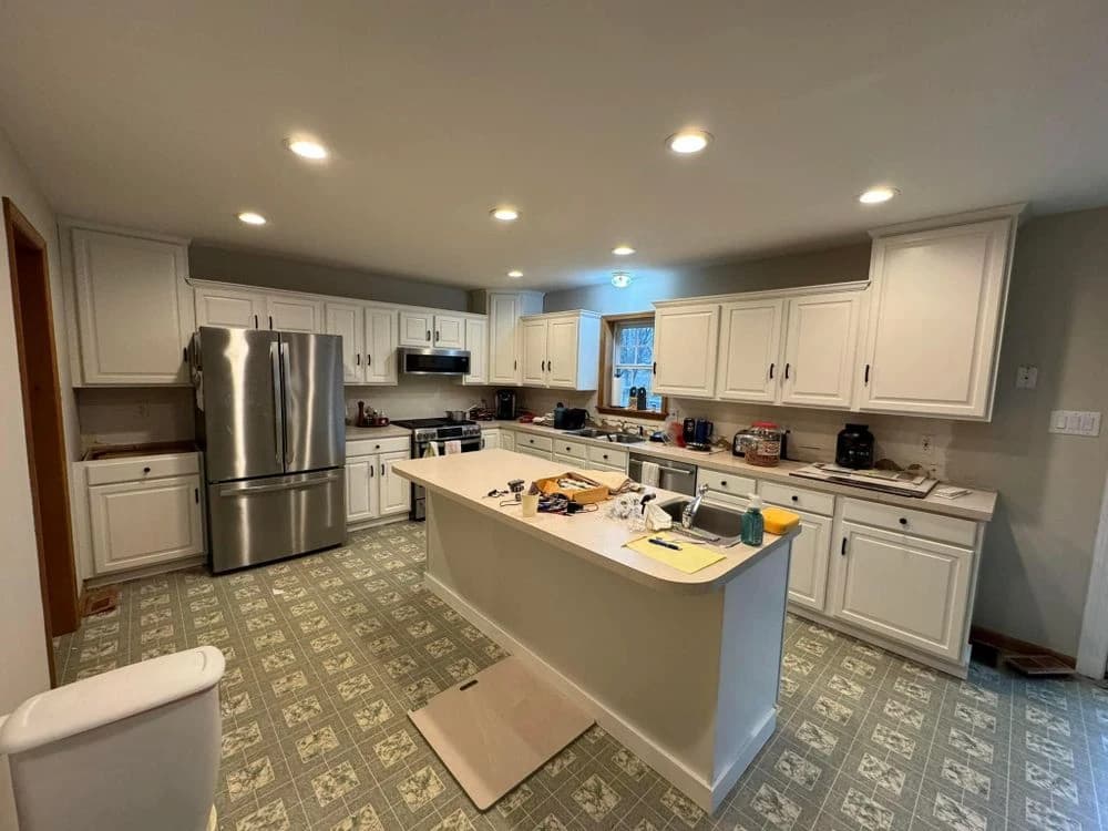 Kitchen renovation in progress with white cabinets, an island, and new countertops, highlighting home improvement and painting services by Painting Plus Home Improvement LLC.