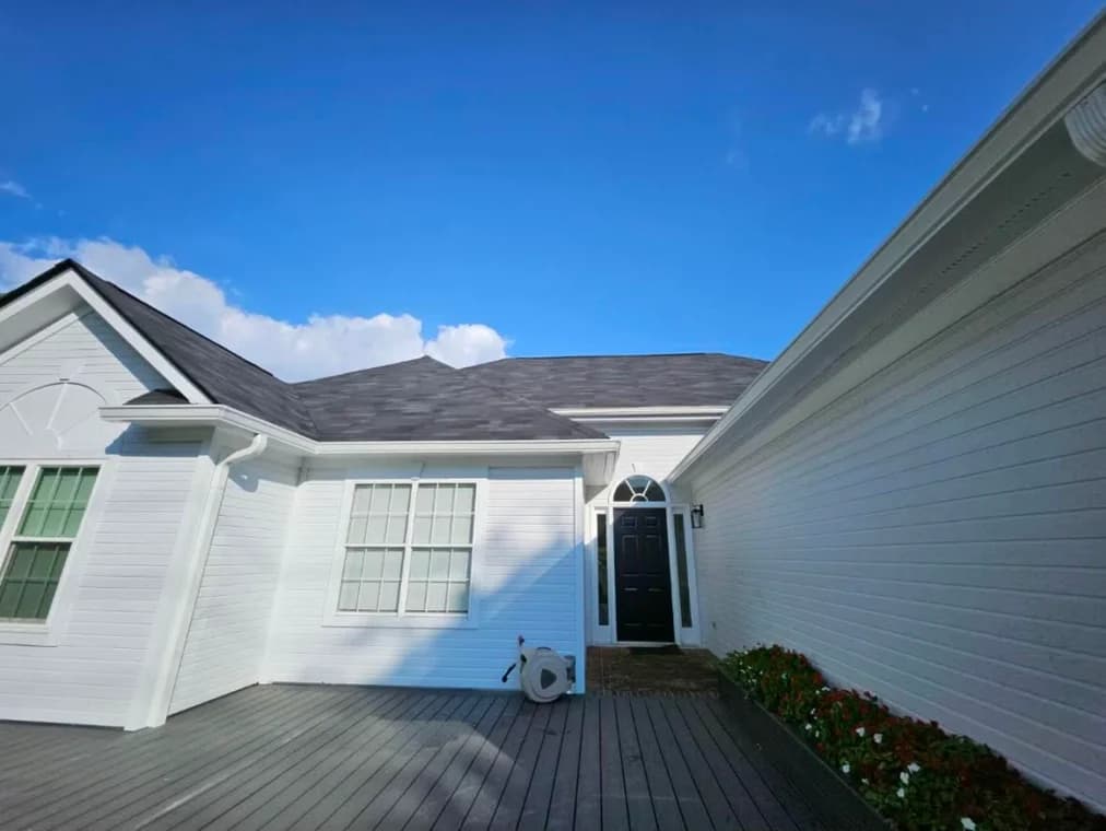 This is an image from Goodpaster Painting & Guttering, located in Tennessee. The image is a bright white exterior home with dark shingles and clean trim repainted by Goodpaster Painting & Guttering.