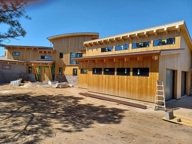 This is an image from All Painting Plus 2, LLC company, located in Colorado Springs, CO The image is a mModern home exterior with natural wood siding and large windows painted by All Painting Plus 2 LLC in Colorado, highlighting professional residential painting and staining services.