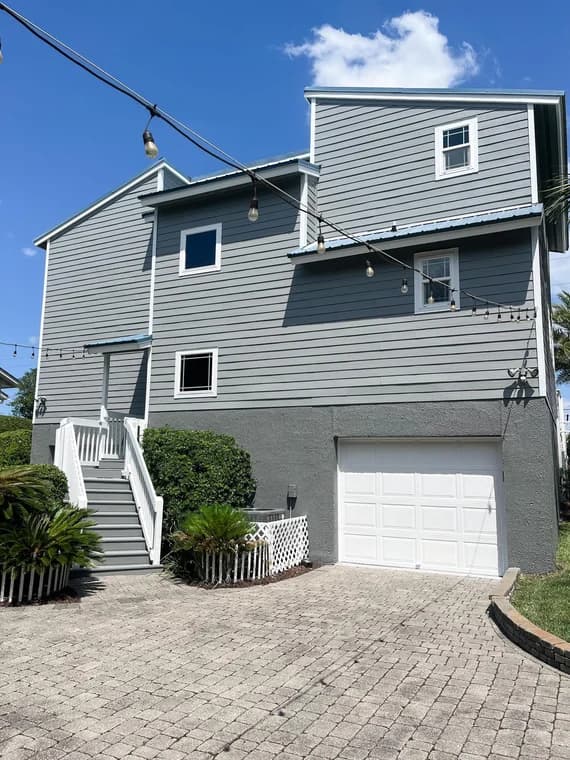 This is an image from Halls Quality Painting company, located in Fernandina Beach, FL. The image is a freshly painted two-story coastal-style home with gray siding, white trim, and white garage door, completed by Hall’s Quality Painting in a residential exterior painting project.