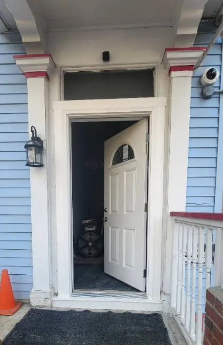 This is an image from Nkomo Painting and Contracting, located in Massachusetts. The image shows a freshly painted front entry with light blue exterior siding, white trim, red accent details, and a newly installed white door.