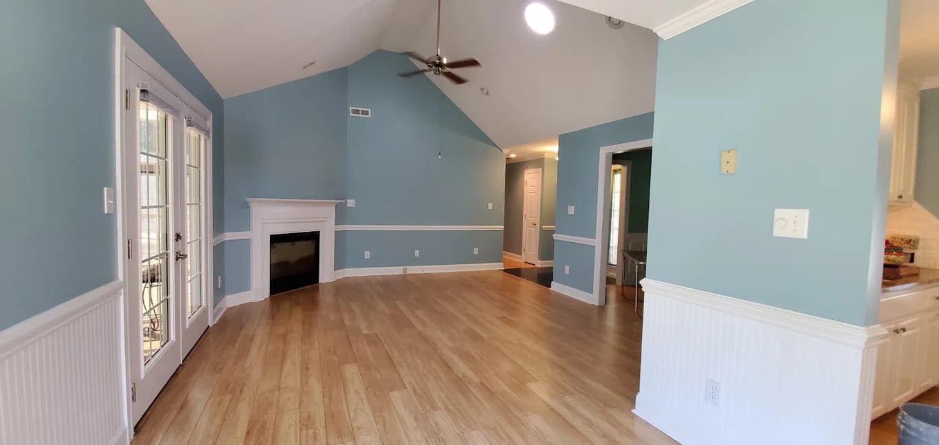 Interior painting project by C&A Home Contractors LLC in Charlotte, North Carolina. The image shows blue walls, white trim, fireplace, and wood floor.