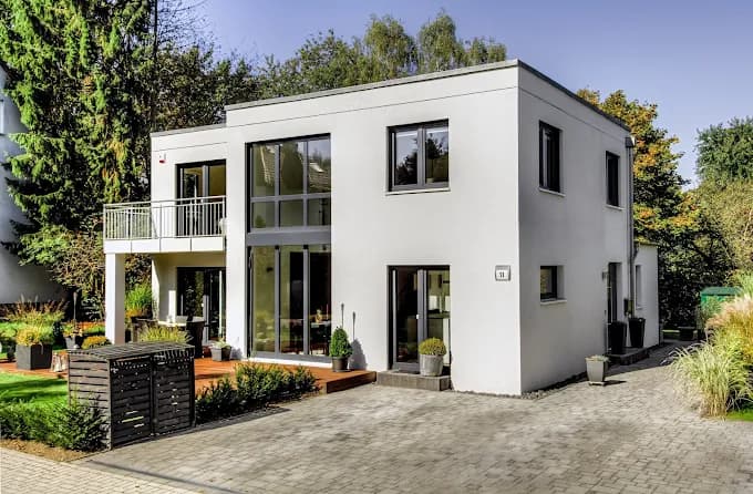 This is an image from Five Star Painting, featuring a modern white-painted cubic-style home. Large windows and clean lines emphasize the minimalist design, with the fresh exterior paint providing a sleek and polished look.