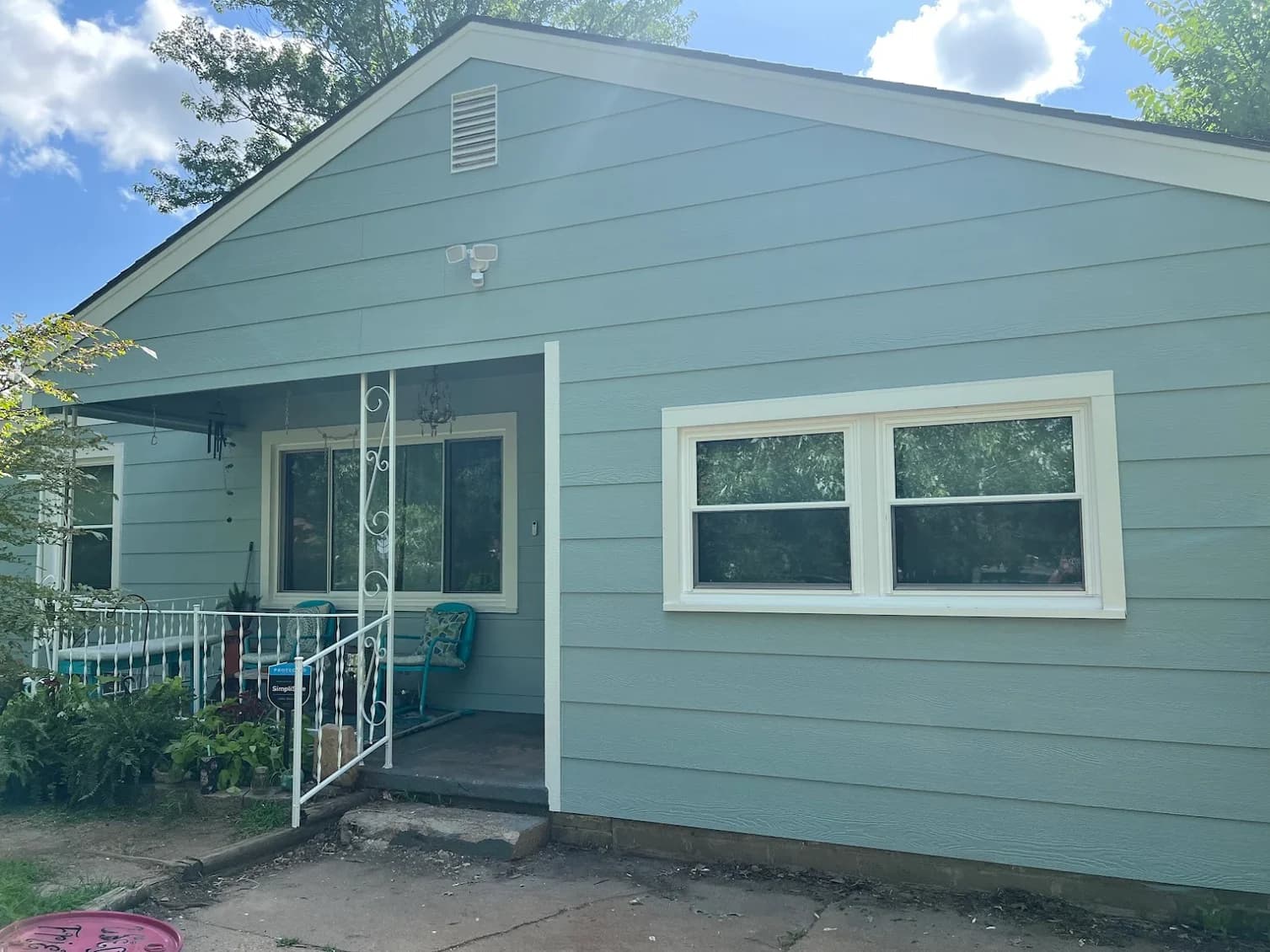 This is an image from Northwind Painting LLC. The image shows a small light-blue house with clean white trim and a freshly painted front porch area.