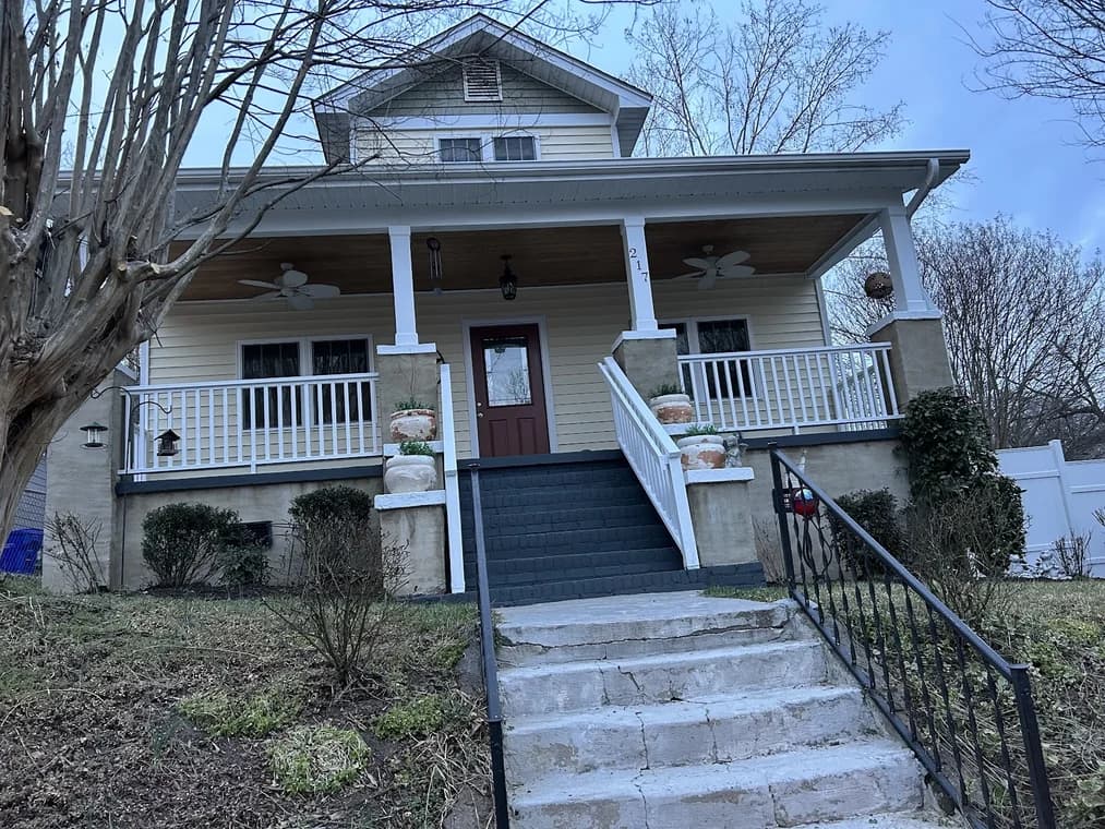 Finished porch-front home exterior with light siding, white railings, dark steps, and trim by Paint EZ of Durham.