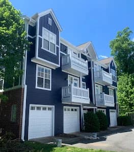 Exterior painting project by Perfection Painting Pros in Charlotte, NC. The image shows a dark blue townhome with white trim and garages.