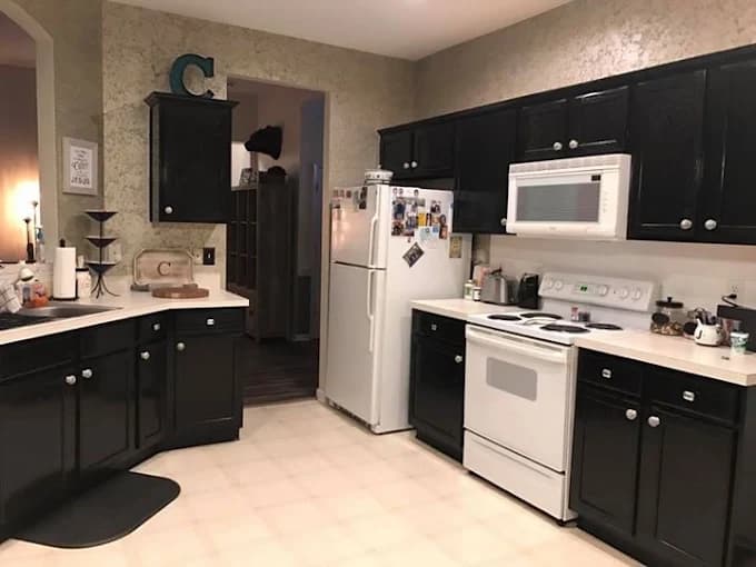 Cabinet painting project by Still Perfection Painting Co. in Belews Creek, North Carolina. The image shows black cabinets, white appliances, and light counters.