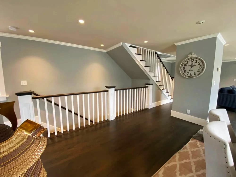 Interior painting project by Paint Guru House Painters in Highland Park, Illinois. The image shows gray walls, white railings, dark wood floors, and a staircase.
