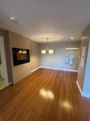This is an image from CertaPro Painters of Boston. It features a freshly painted interior room with beige walls, wood flooring, and modern lighting fixtures.