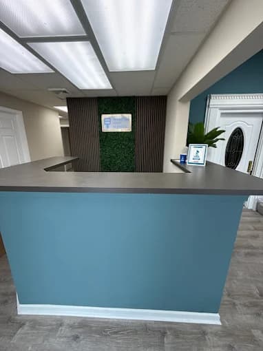This is an image from Advantage Paint Services, located in New York. The image shows a commercial office reception area with blue painted walls, a gray front desk counter, and overhead fluorescent lighting.