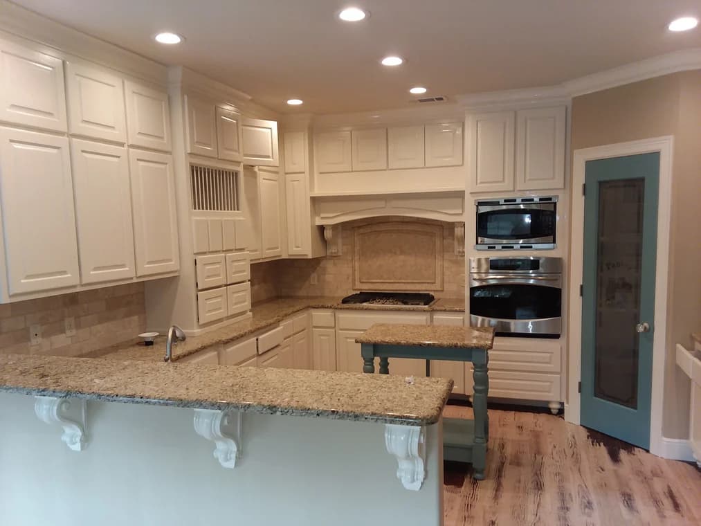 "This is an image from Reeves Painting, located in Texas. The photo shows a renovated kitchen with cream-colored cabinets, granite countertops, and recessed lighting."