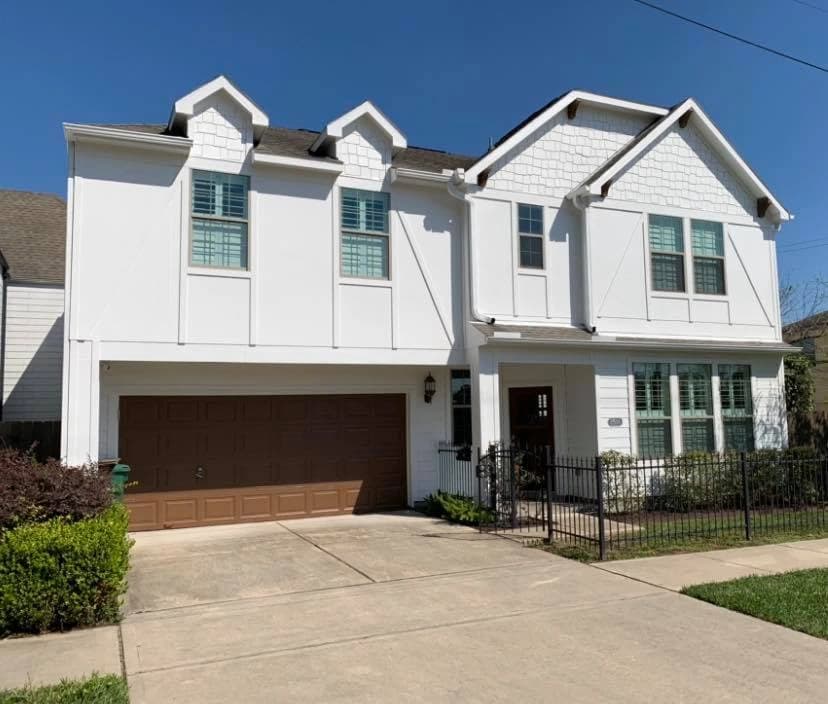 "This is an image from Squared Away Painting, located in Texas. The two-story white home features crisp exterior paint with contrasting brown garage doors and decorative trim details."