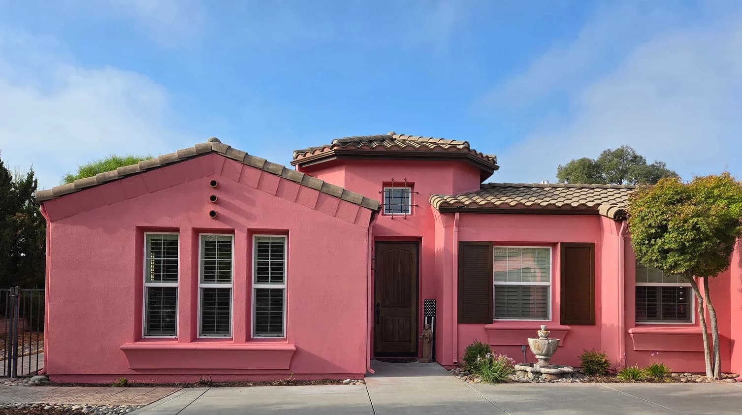 This is an image from Browder Painting Company, located in California. The image shows a freshly painted single-story stucco home exterior with a bold pink finish, dark window shutters, a tile roof, and clean architectural details.