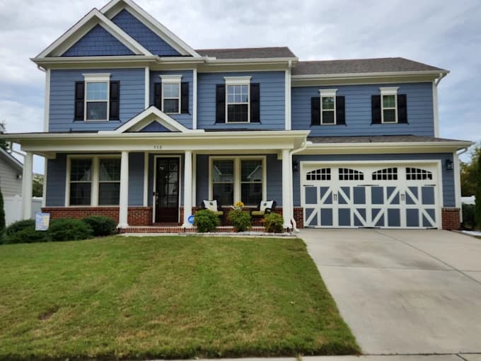 Exterior painting project by Anderson Painting in Raleigh, North Carolina. The image shows blue siding, white trim, shutters, and a garage door.