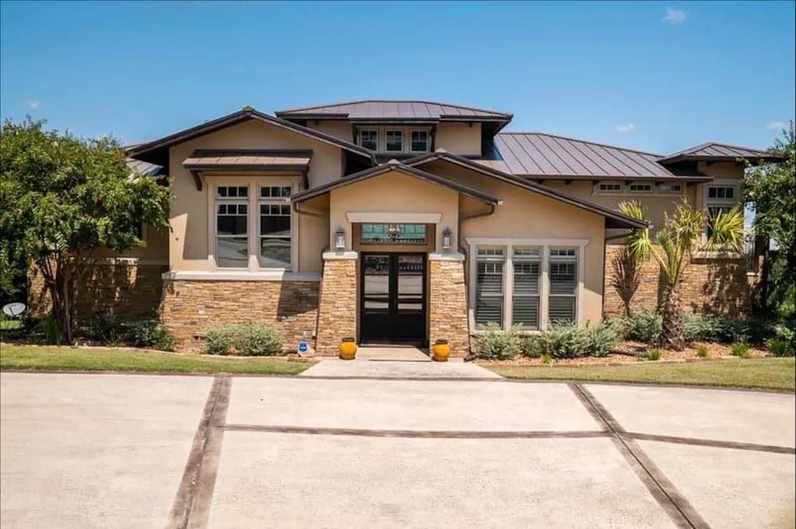 "This is an image from CertaPro Painters of NW San Antonio, located in Texas. The photo shows a large modern beige home with stone accents, wide rooflines, and neatly manicured landscaping."