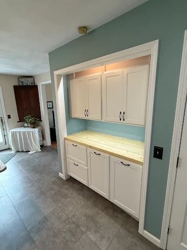 This is an image from Joseph Rivers Painting, located in Ohio. The photo shows a built-in cabinet area with white cabinetry, wood countertop, and a blue accent wall.