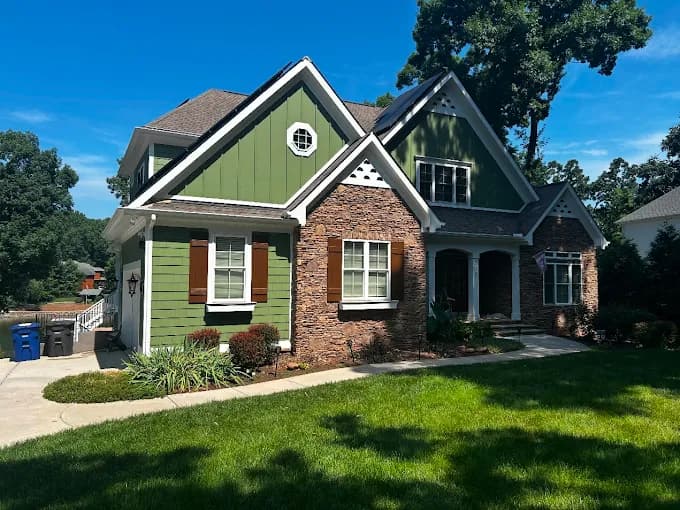 Exterior painting project by Richard's Painting of Mooresville in Mooresville, NC. The image shows a green brick home with white trim.