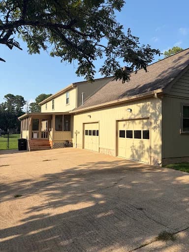 Painting work by Scott Brown Professional Painting & Remodeling in Chattanooga, Tennessee. The image shows a light house exterior with dark garage doors.