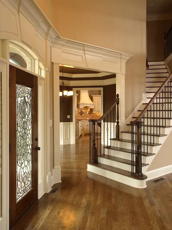 "This is an image from CertaPro Painters of NW San Antonio, located in Texas. The interior entryway features a stained wood front door, decorative molding, hardwood floors, and a staircase with dark wood railing and iron balusters."