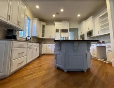 Interior painting project by Avanti Painting LLC in Mooresville, NC. The image shows a kitchen with white cabinets, a gray island, and wood floors.