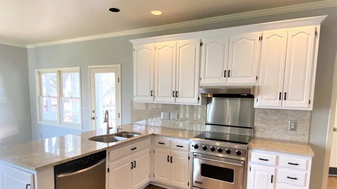 This is an image from Cougar Painting LLC. The image is interior kitchen in Kansas City KS with freshly painted white cabinets and marble countertops.